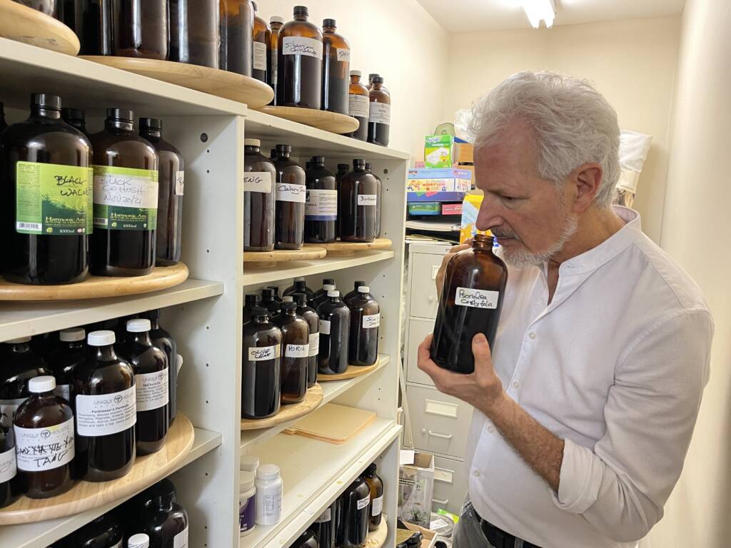 Dr. Neil Tessler is shown inspecting his herbal extractions for botanical medicine. 